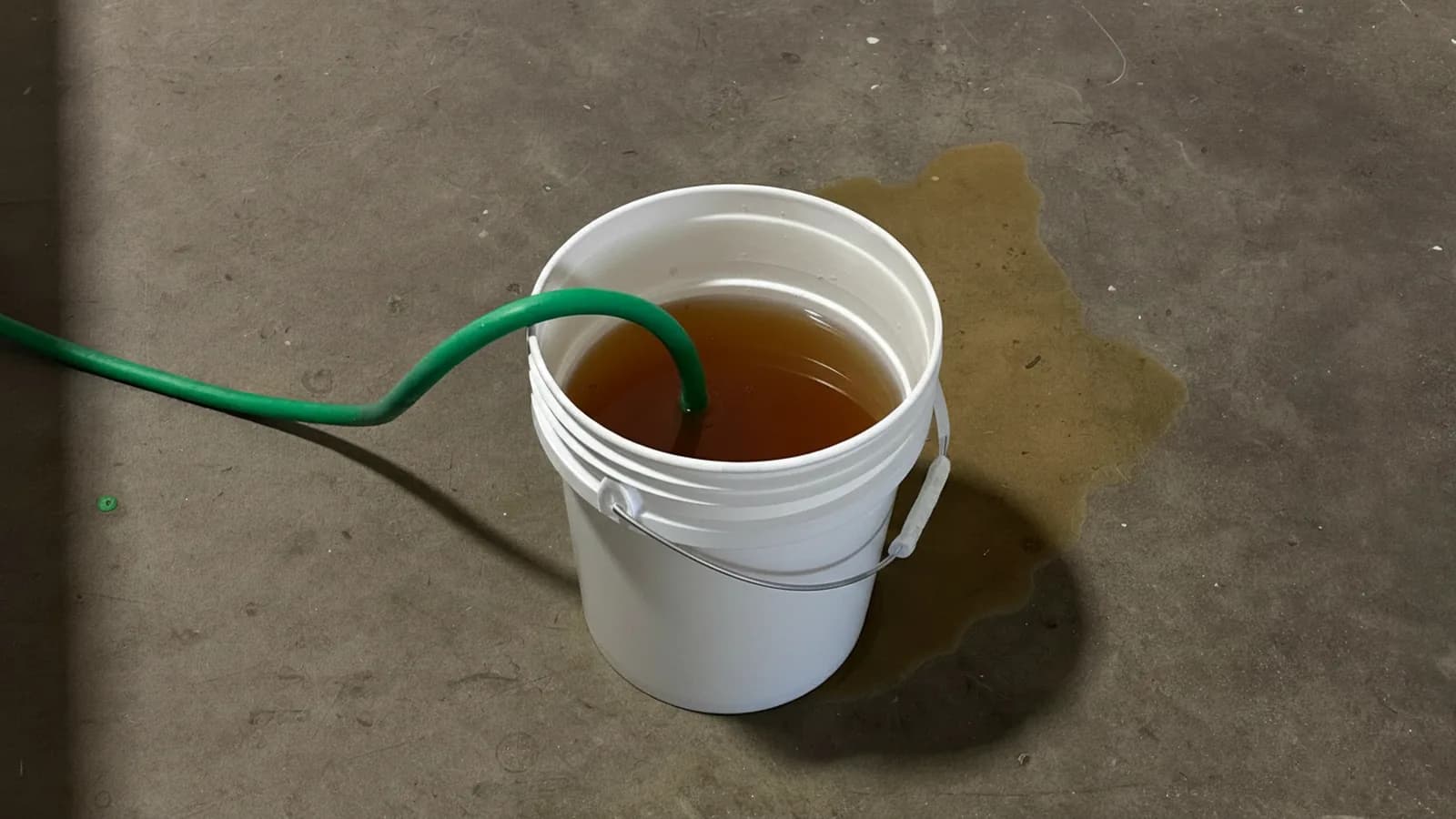 Bucket of murky rust-brown water flushed from a tank water heater onto a Massachusetts basement floor